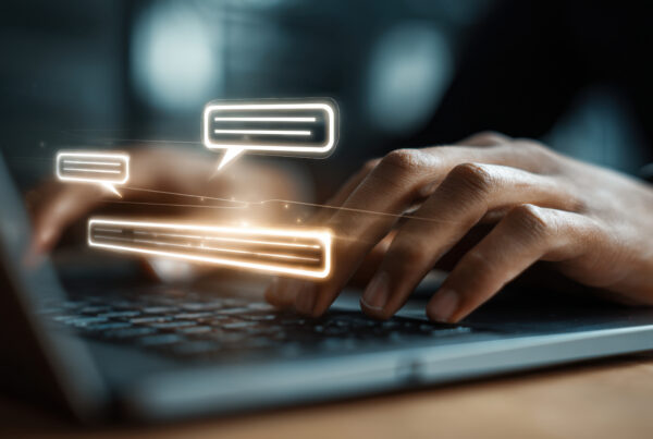 Person typing on a computer keyboard with chat bubbles overlayed on the screen.