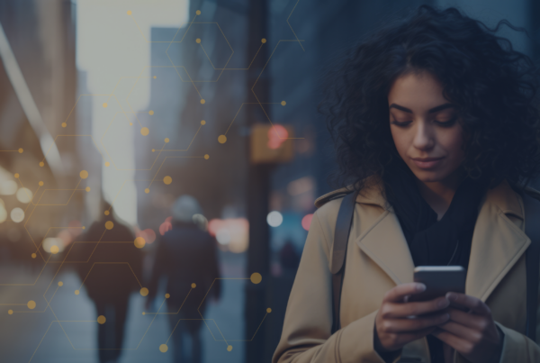 Professional woman looking down at her mobile phone against blurred city setting.